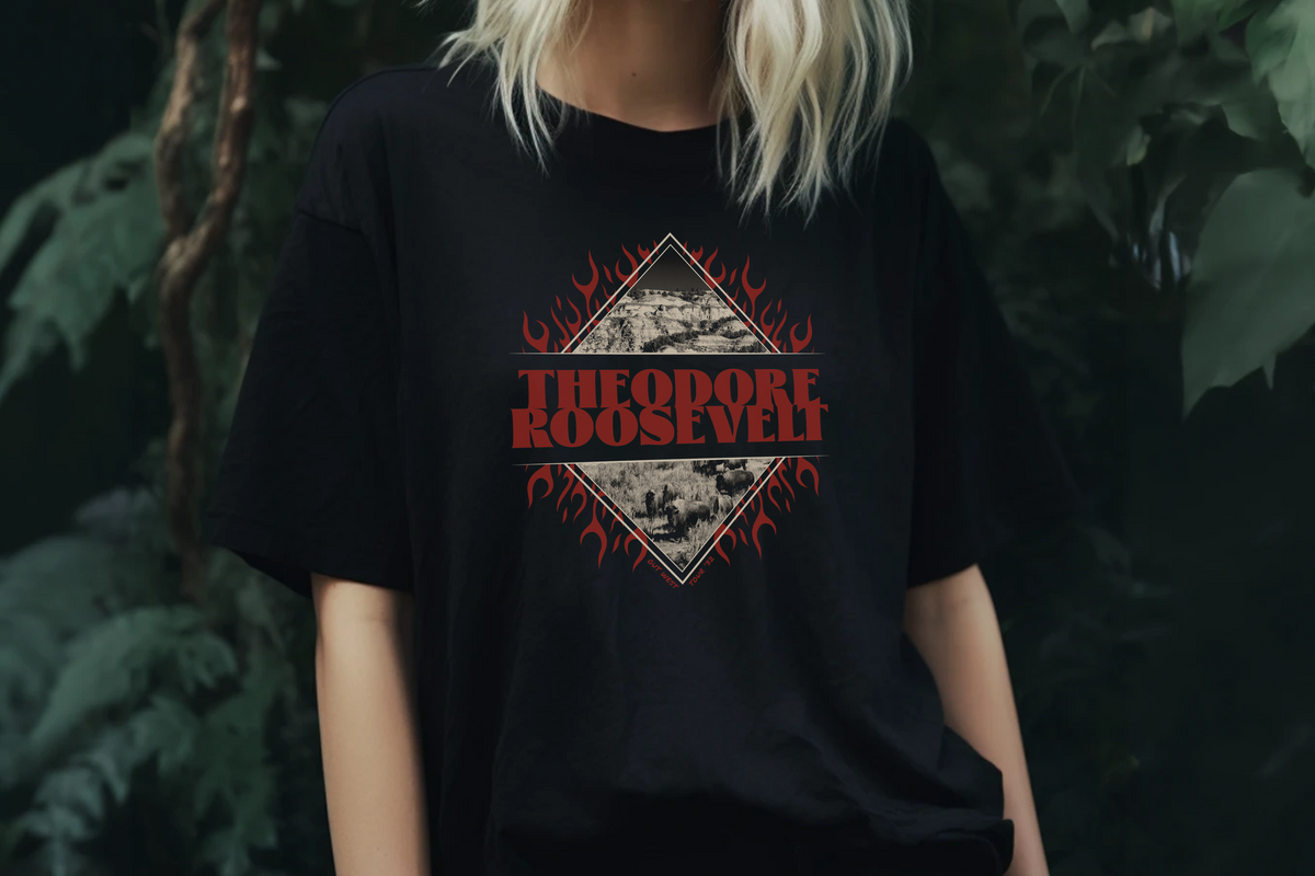 Person wearing a black t-shirt with 'Theodore Roosevelt' graphic design, standing in front of a plant background