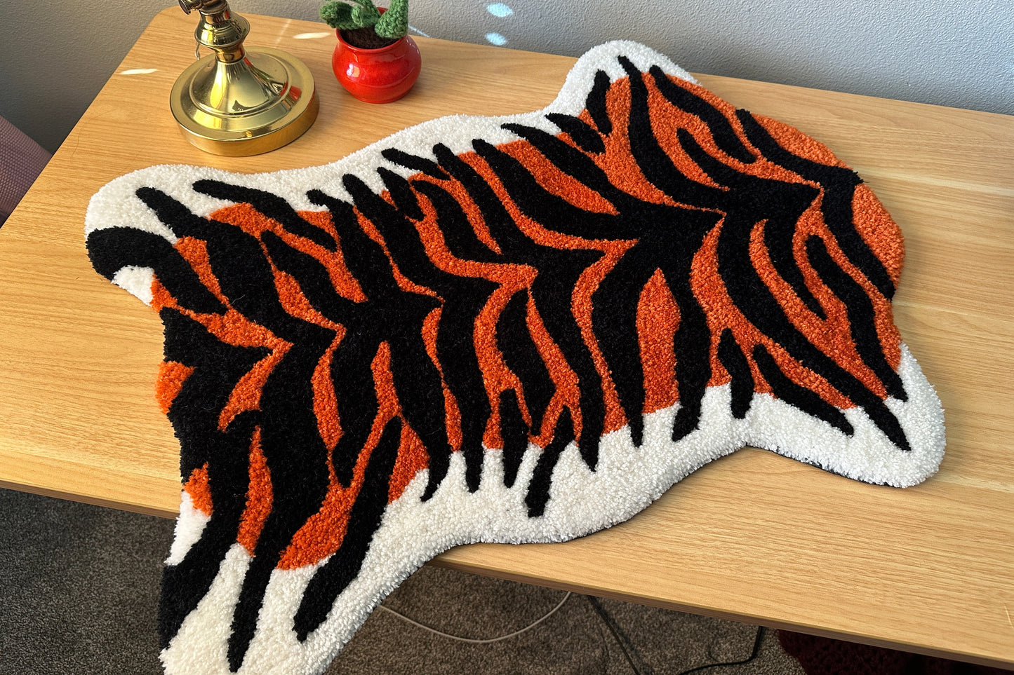 Tiger stripe patterned rug on a wooden surface with decorative items.