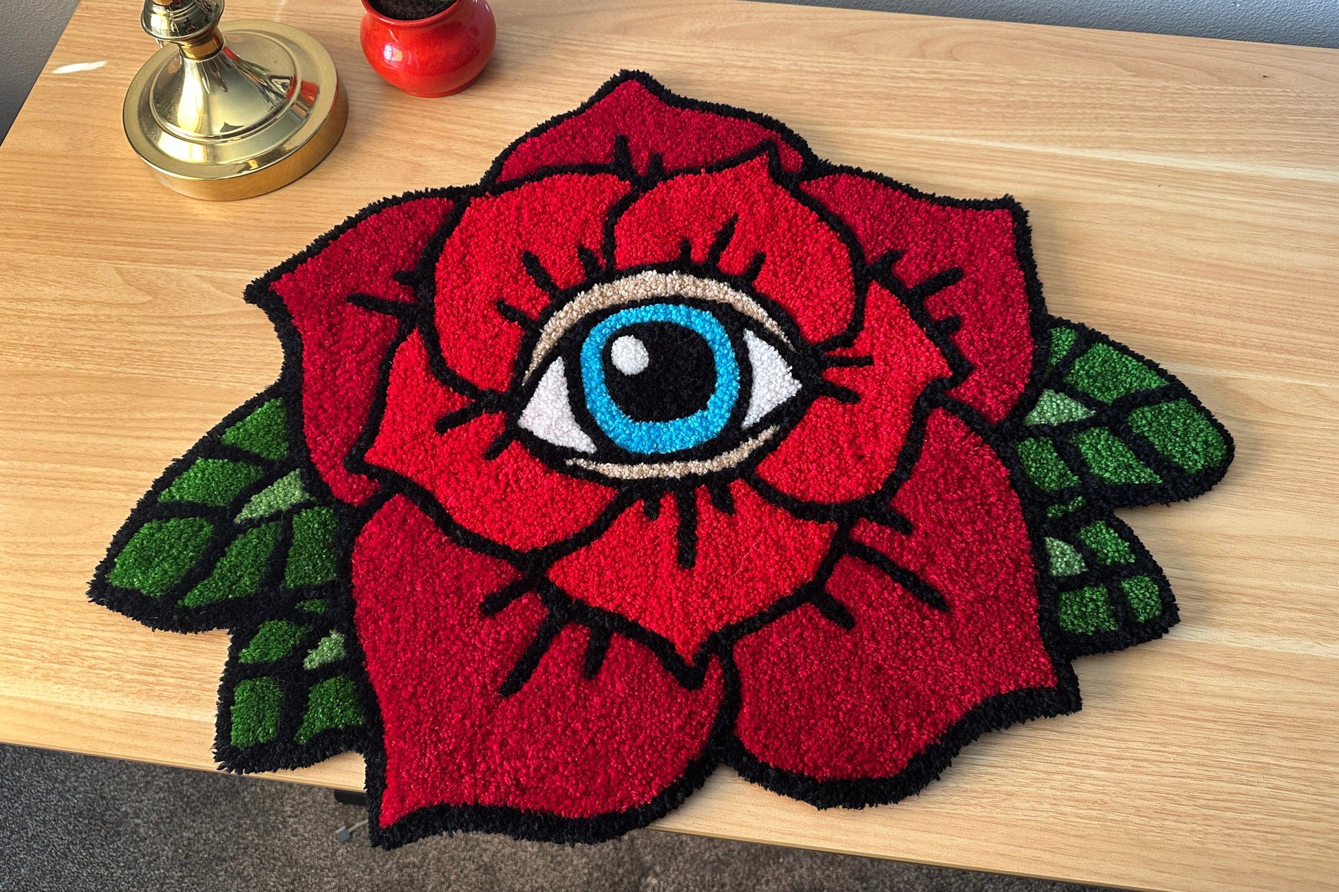 Tufted ed rose with an eye design on a wooden surface