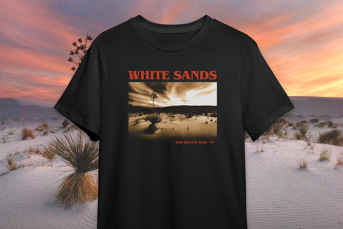 Black t-shirt with White Sands design against a desert landscape background