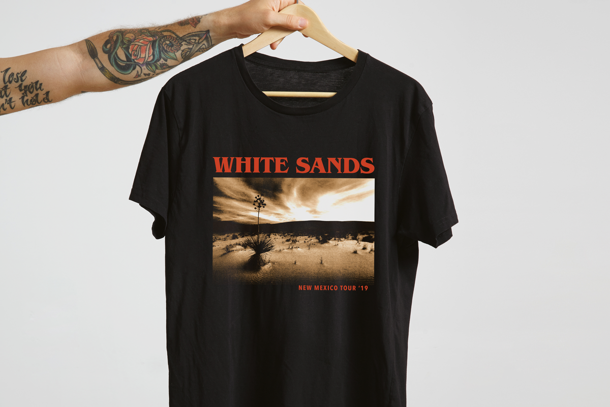 Black t-shirt with 'White Sands' graphic design on a hanger against a white background