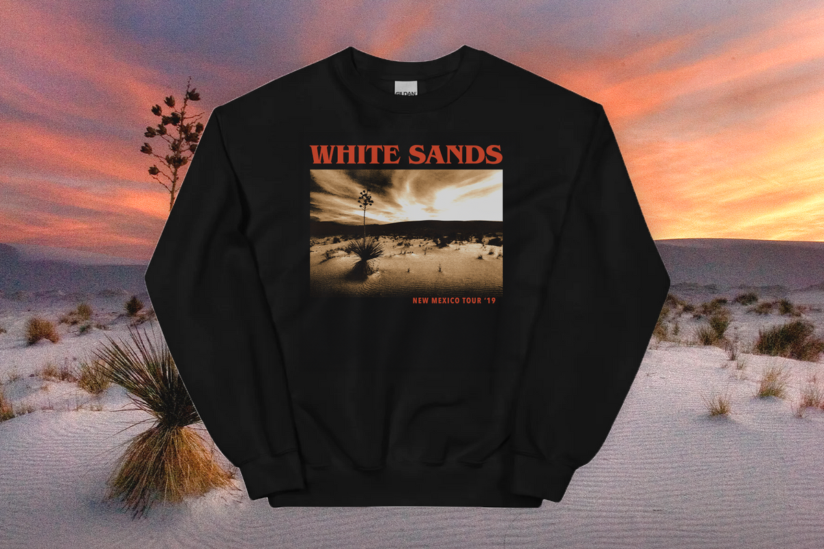 Black sweatshirt with 'White Sands' design against a desert landscape backdrop