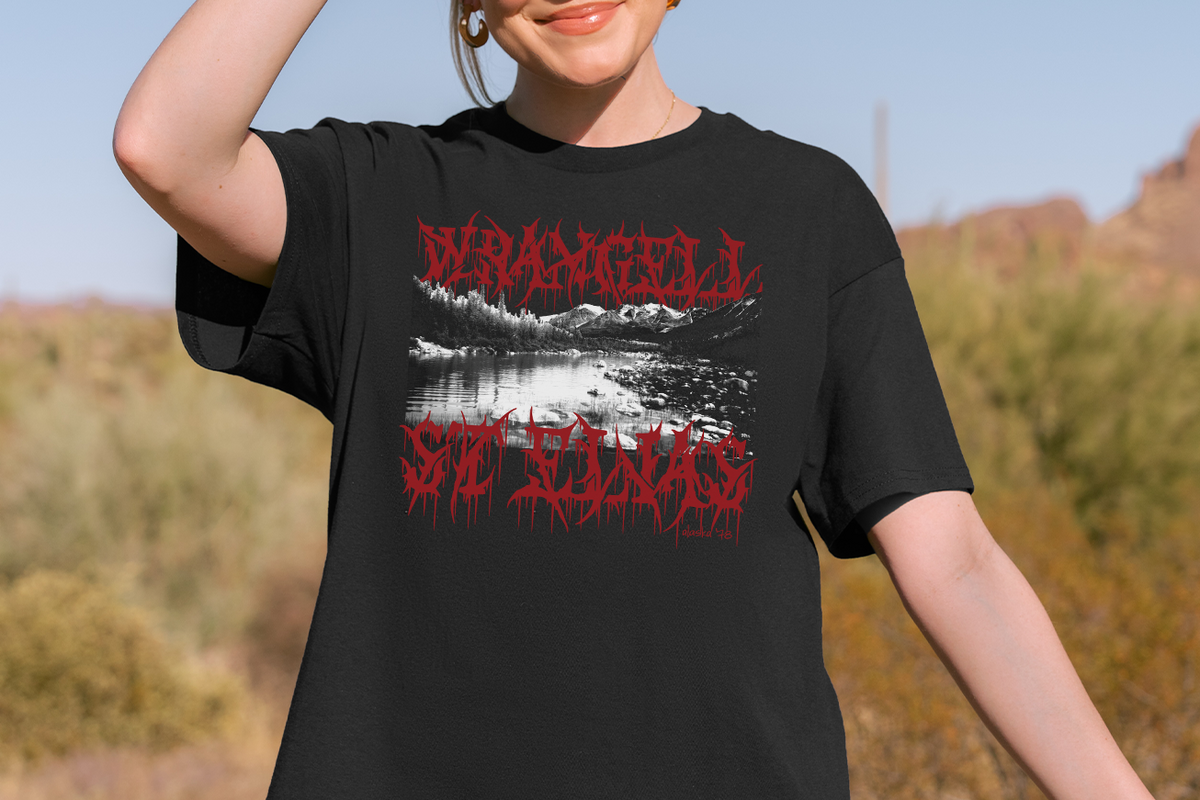 Person wearing a black t-shirt with red 'Wrangell St Elias'  and white graphic design outdoors