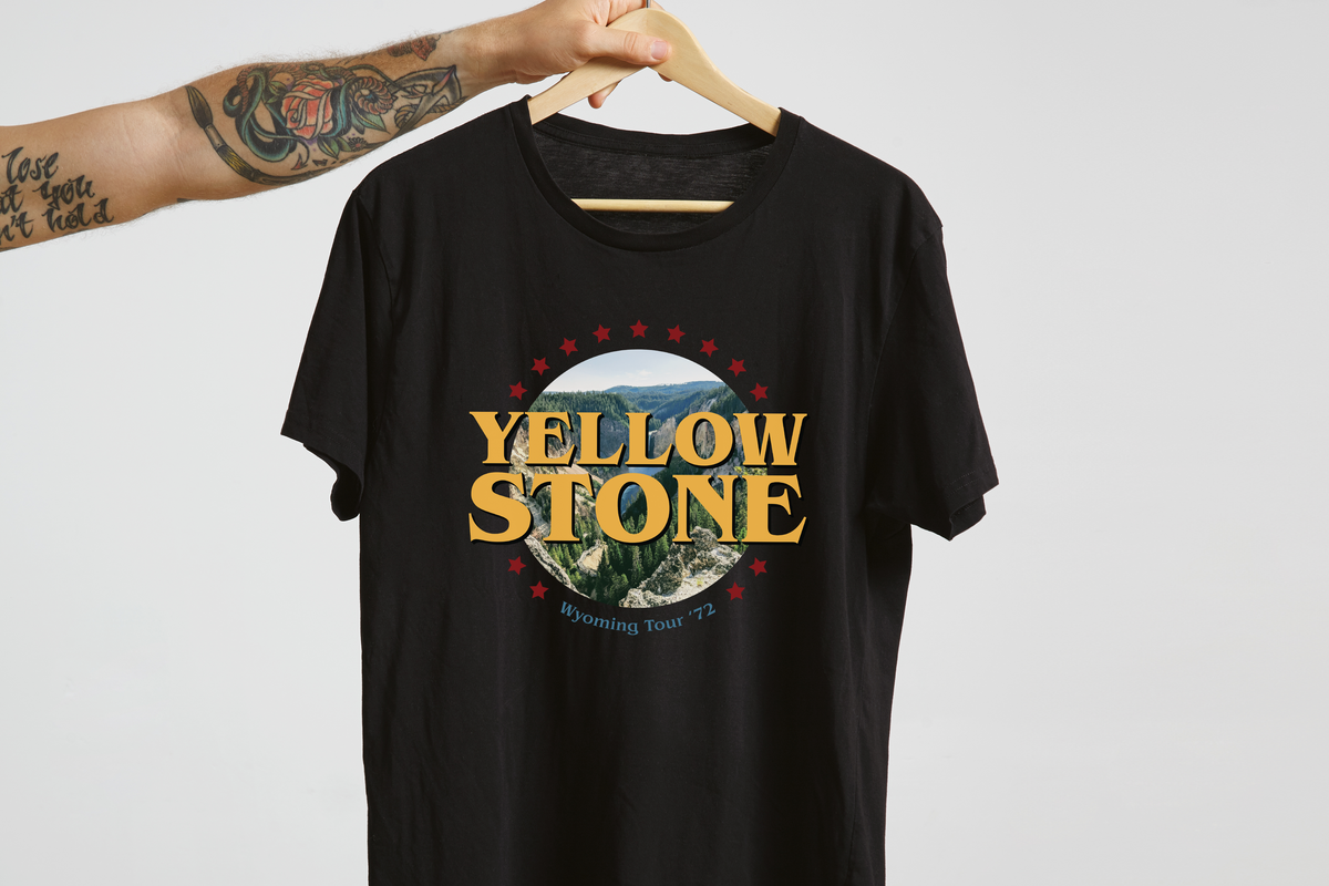Black t-shirt with Yellowstone graphic on a hanger against a white background
