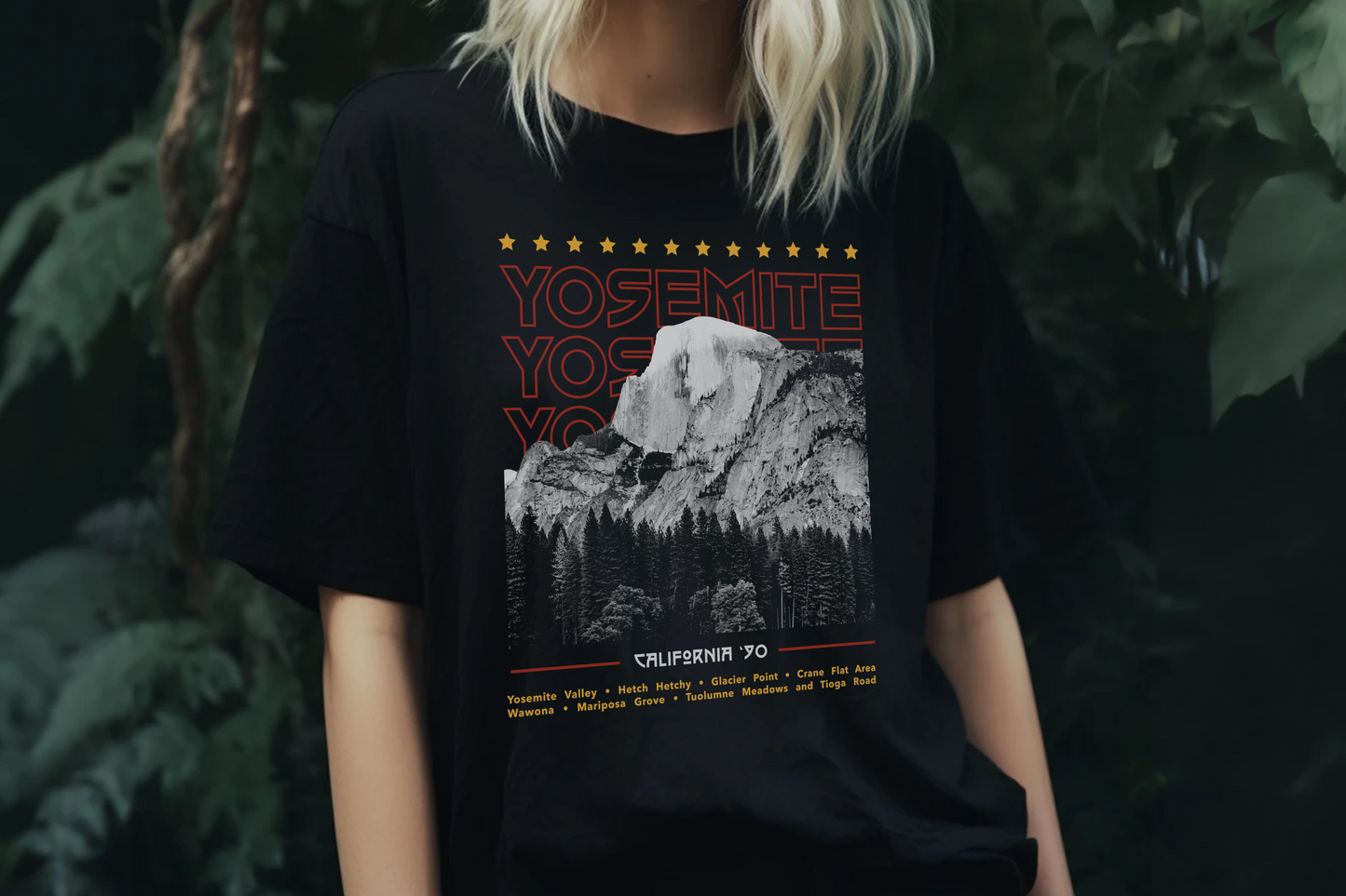Person wearing a black t-shirt with Yosemite design in front of green foliage