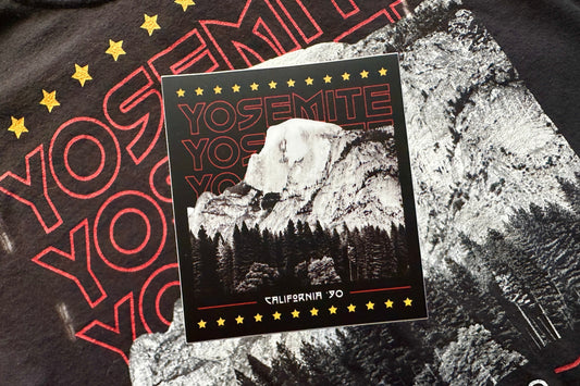 Black sticker with a red and white 'Yosemite' design, in front of a textured background