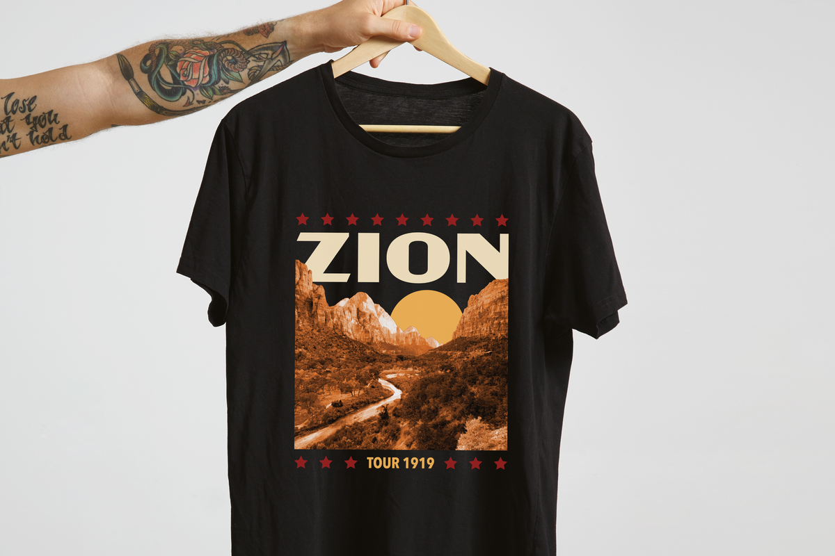 Black t-shirt with 'Zion National Park' graphic design on a hanger against a white background
