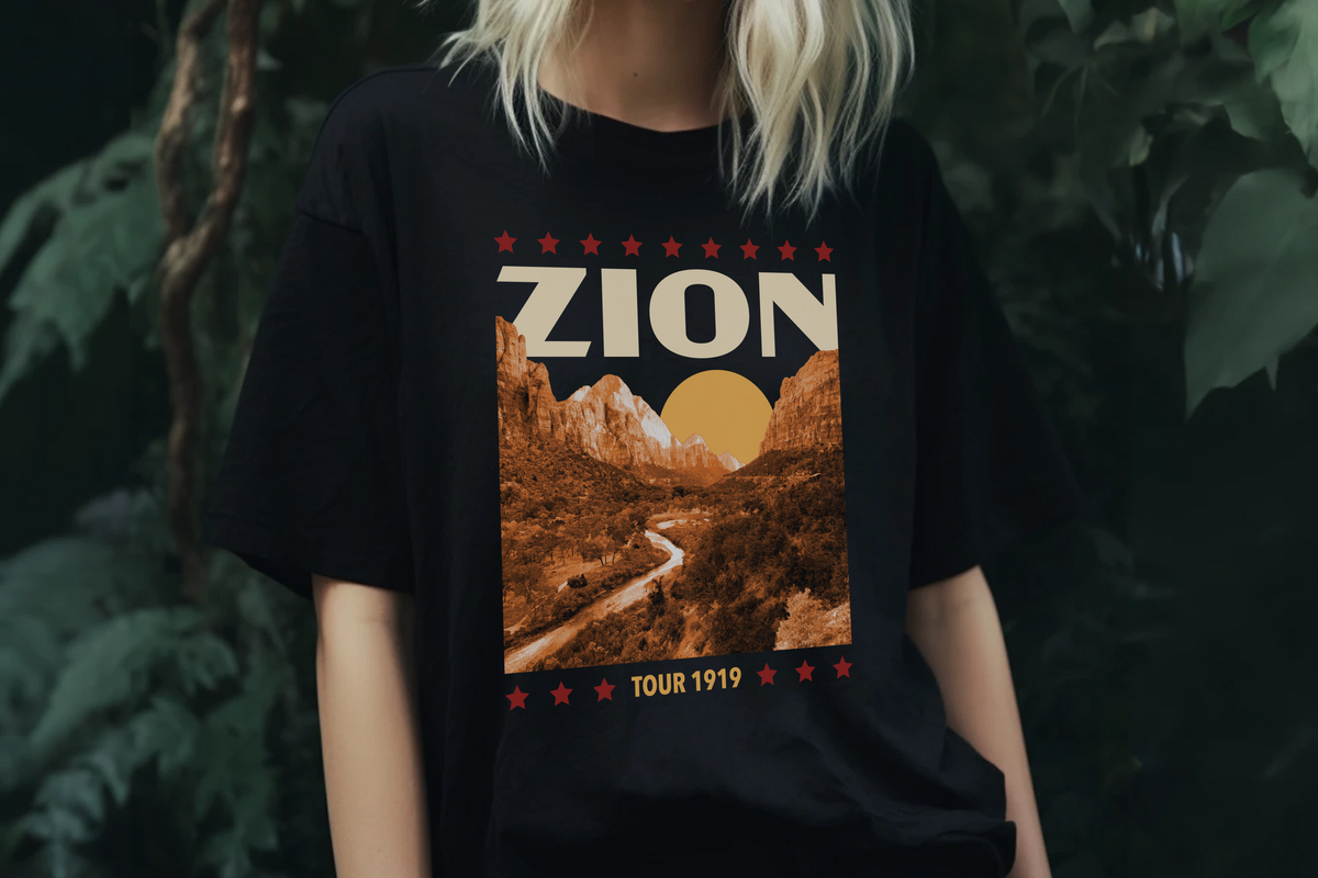 Person wearing a black t-shirt with 'Zion' and mountain graphic design, standing in front of plants
